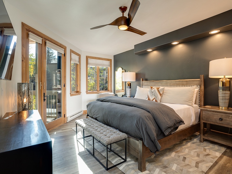 Step into your serene bedroom retreat, where a plush king bed, stylish decor, and natural light through the balcony doors invite you to unwind in comfort.