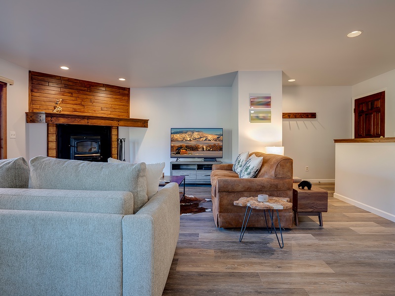 Settle into your open-concept living space, where a warm wood-burning fireplace, plush seating, and stunning mountain views create the perfect retreat after exploring.