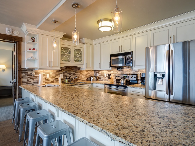 Spread out and savor your mornings in this bright, fully equipped kitchen featuring granite countertops, stainless steel appliances, and a spacious island with seating for casual dining.