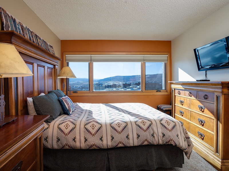 Wake up to sweeping mountain vistas from your comfortable bed, framed by warm wood furnishings and soft lighting that make every morning feel special.