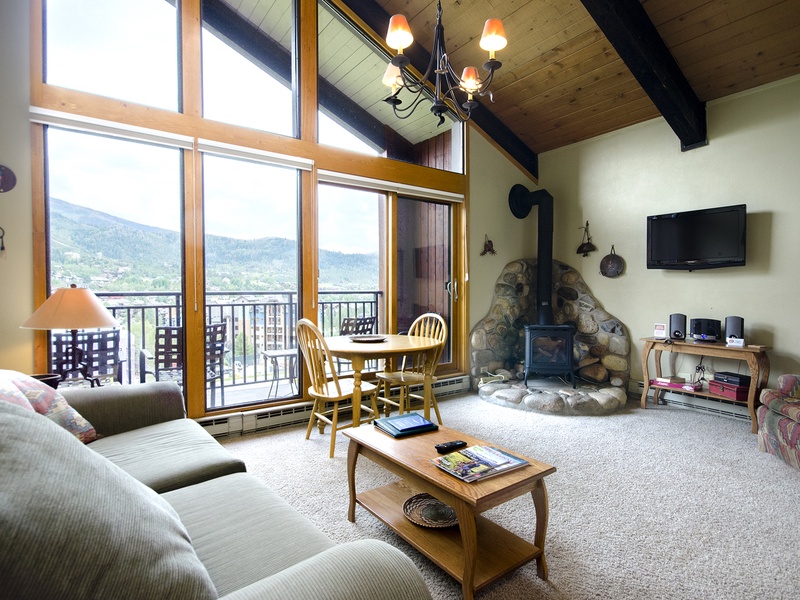 Settle into your spacious living room with soaring ceilings, cozy fireplace, and breathtaking mountain views through floor-to-ceiling windows. Your perfect mountain getaway awaits.
