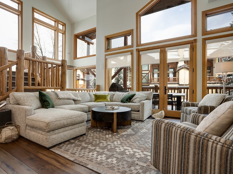 Sink into plush sofas in this stunning mountain retreat, where soaring windows frame snowy forest views and rustic log accents create your perfect alpine escape.