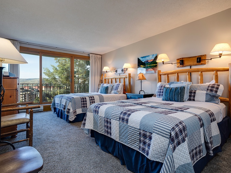 Settle into your cozy alpine retreat with rustic log headboards, plaid quilts, and scenic mountain views through your private balcony—perfect for peaceful mornings and starry evenings.