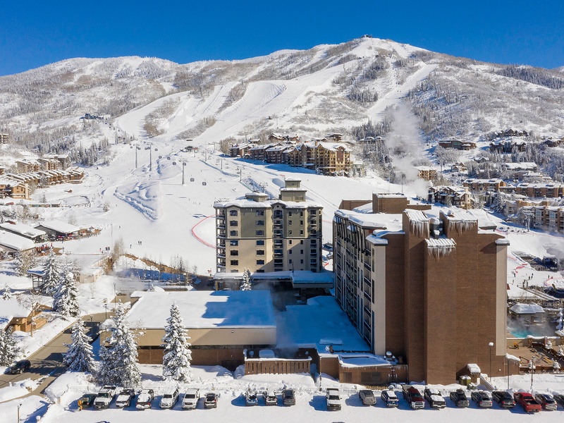 Ski resort nestled in snow-covered mountains with slopes and lifts visible. Winter destination surrounded by frosted trees and alpine lodges.