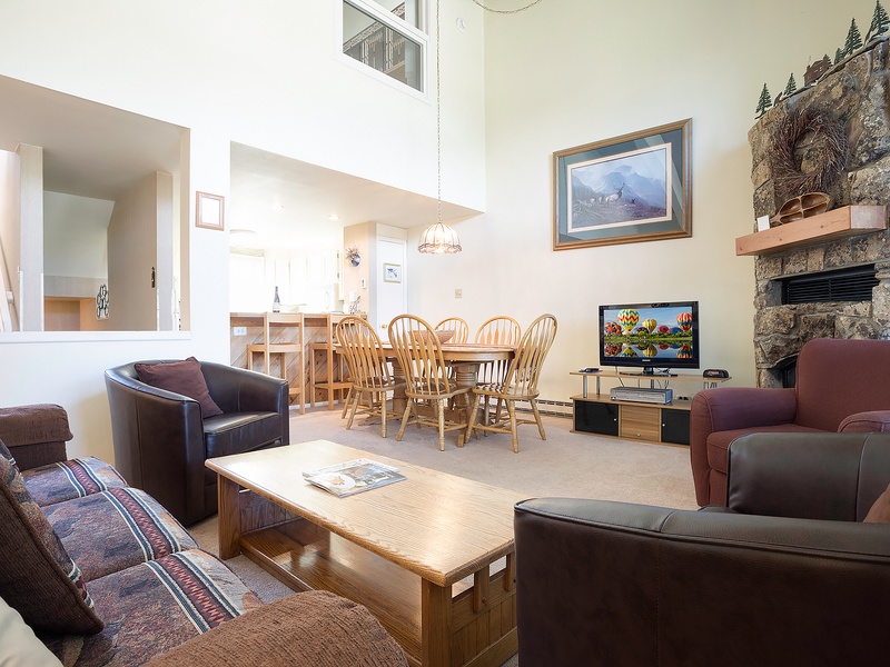 Gather with loved ones in your spacious living area, where soaring ceilings and a stunning stone fireplace create a warm, inviting atmosphere for memorable conversations and cozy evenings together.