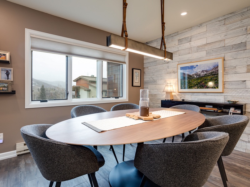 Gather around this stylish oval table for meals or conversation, surrounded by modern comfort and natural mountain light streaming through your window.