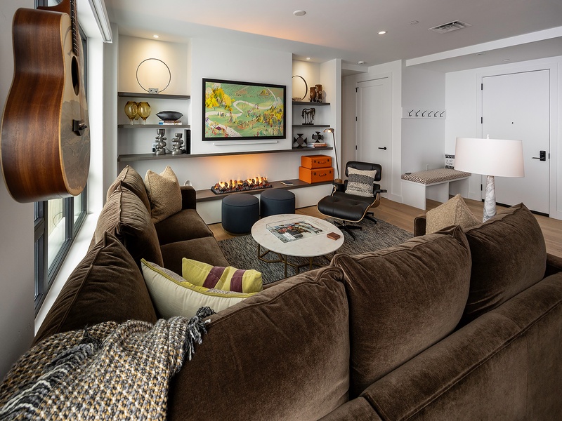 Settle into this inviting living space where modern design meets personal comfort. Sink into plush seating near the warm glow of the fireplace, strum the guitar, or simply unwind surrounded by curated art and thoughtful details.