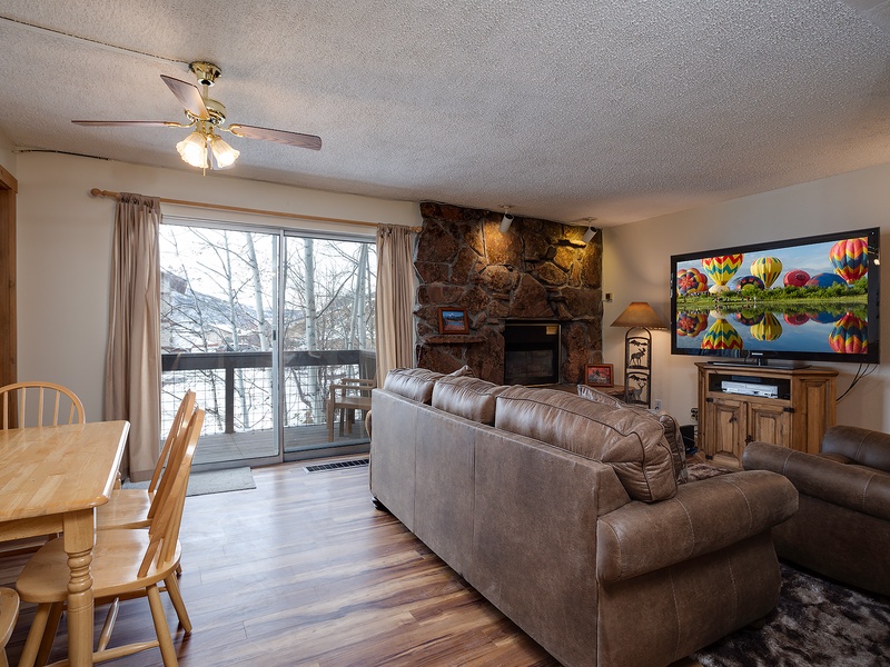 Unwind in your cozy living room with a stunning stone fireplace and large windows framing peaceful winter views. Settle into plush seating for movie nights or simply enjoy the serene ambiance.
