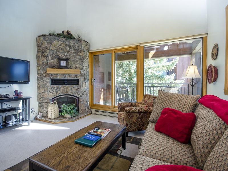 Relax in your spacious living room with a cozy stone fireplace, mountain views through sliding glass doors, and comfortable seating—perfect for unwinding after a day of adventure.