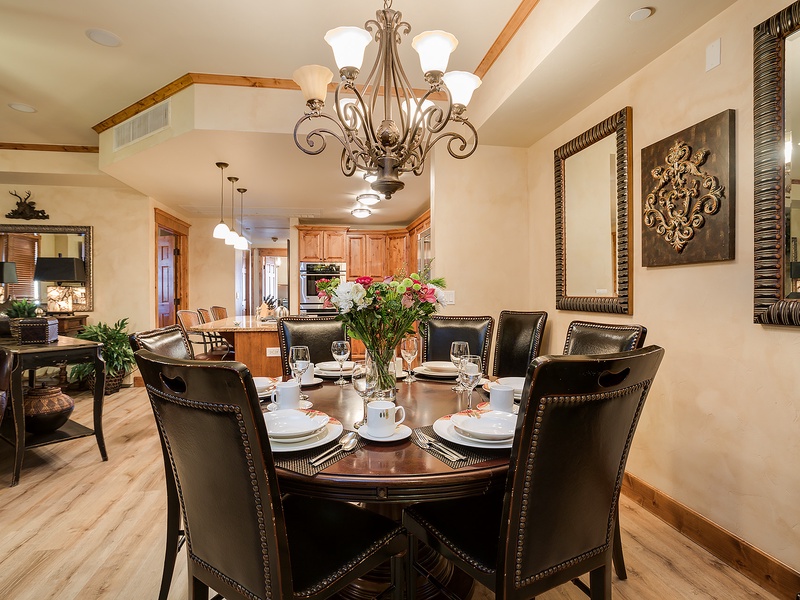 Gather around this elegant dining table for memorable meals together, where a stunning chandelier and thoughtful décor create the perfect setting for your group's shared moments.