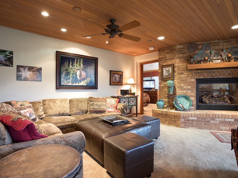 Sink into plush seating by your private fireplace, where rustic charm meets modern comfort. The warm wood ceiling and cozy décor create your perfect retreat after exploring nearby adventures.