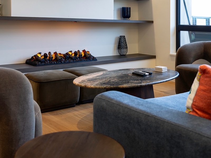 Unwind in your private living room where a modern fireplace casts a warm glow over plush seating and natural textures, inviting you to relax after a day of exploring.