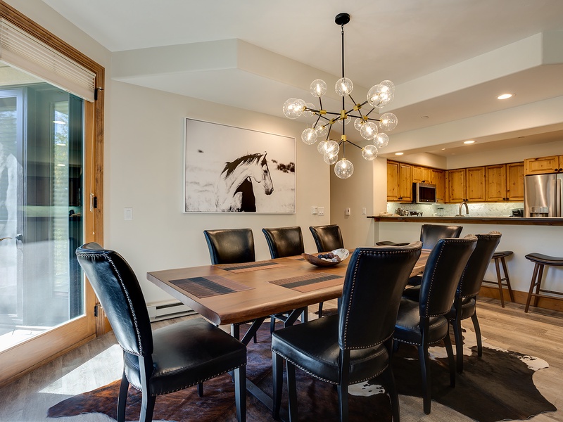 Gather around your beautiful dining table beneath elegant lighting, where meals become memorable moments with family and friends in this stylish open-concept space.