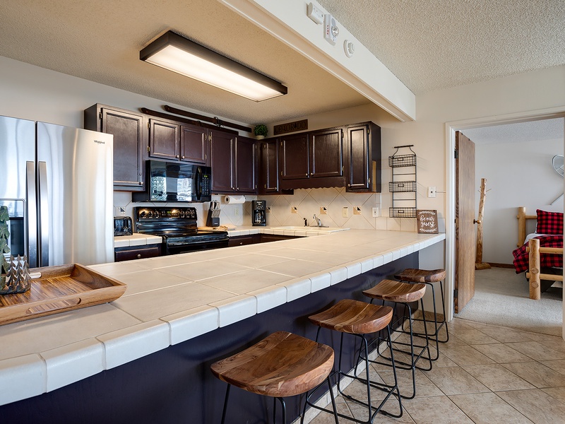 Gather your group around this spacious kitchen island, perfect for morning coffee or meal prep. Dark wood cabinets and modern appliances await your culinary adventures.