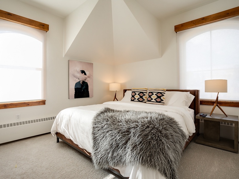 Sink into plush bedding and soft textures in your serene retreat. Natural light pours through arched windows, framing cozy modern touches that invite pure relaxation.