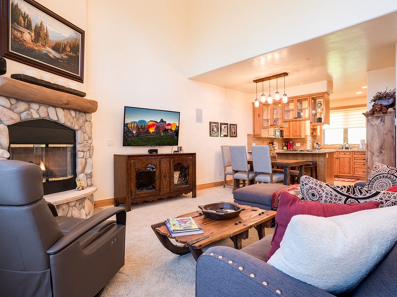 Sink into your cozy living space where a stone fireplace, comfortable seating, and open kitchen create the perfect mountain retreat for relaxing evenings together.