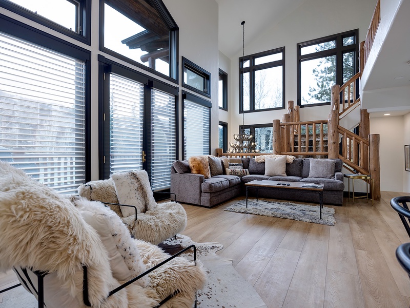 Sink into plush seating surrounded by soaring windows that frame snowy mountain views. Natural light fills your space, where cozy textures and modern mountain design create your perfect alpine retreat.
