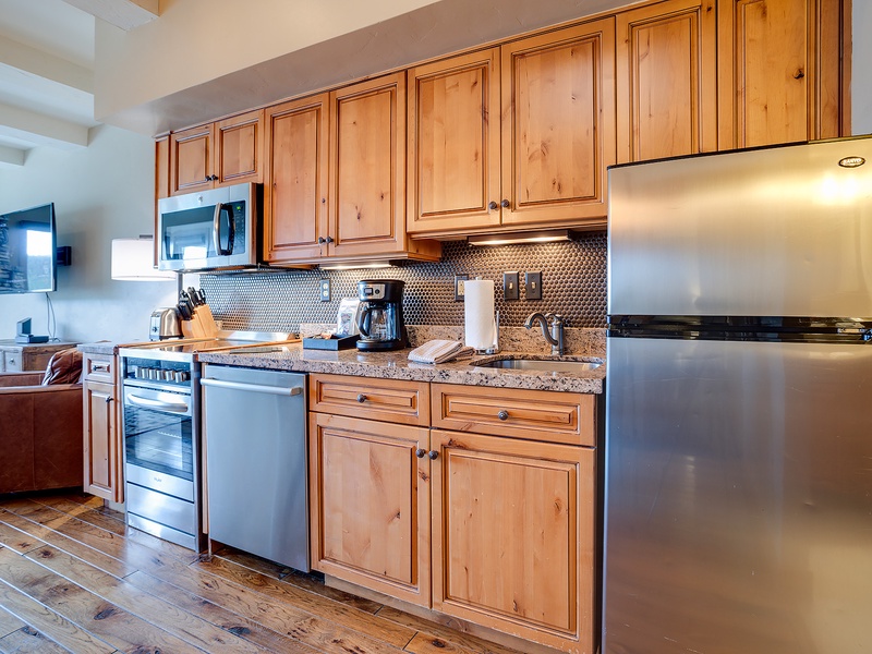 Your fully equipped kitchen features stainless steel appliances, granite counters, and warm wood cabinetry—perfect for morning coffee or preparing home-cooked meals during your stay.