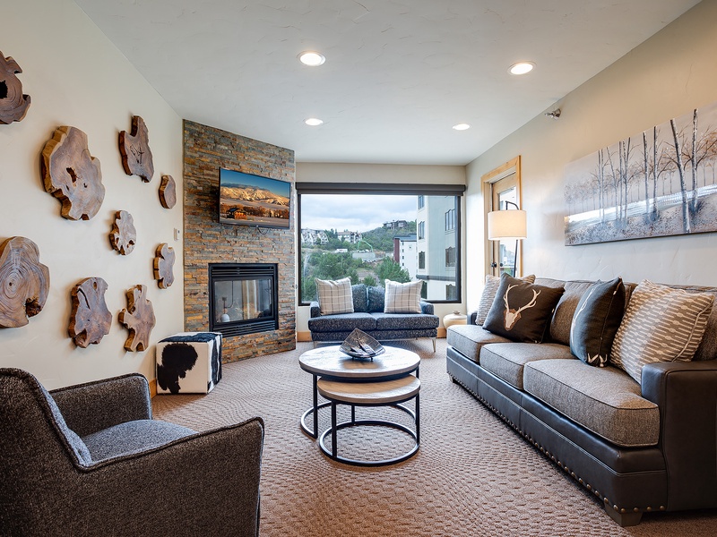 Settle into your modern living room where warm textures and mountain views meet. A cozy fireplace, plush seating, and natural wood accents create your perfect retreat after a day exploring.