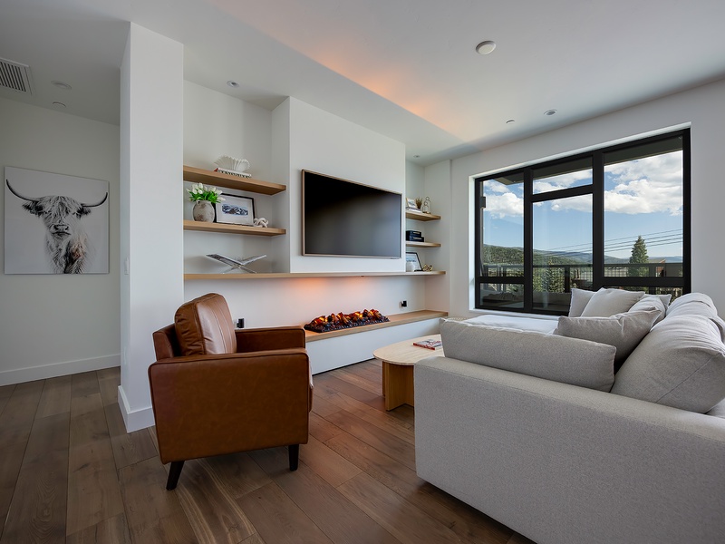 Unwind in this modern living room with a cozy fireplace and plush seating, where you can soak up mountain views through expansive windows.