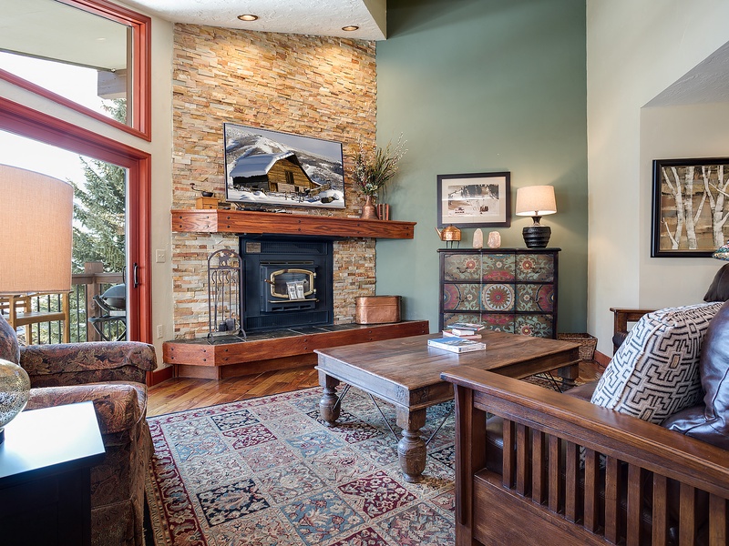 Sink into cozy seating by the warm stone fireplace while taking in the mountain views through soaring windows. Your perfect alpine retreat awaits with rustic charm and comfortable furnishings.