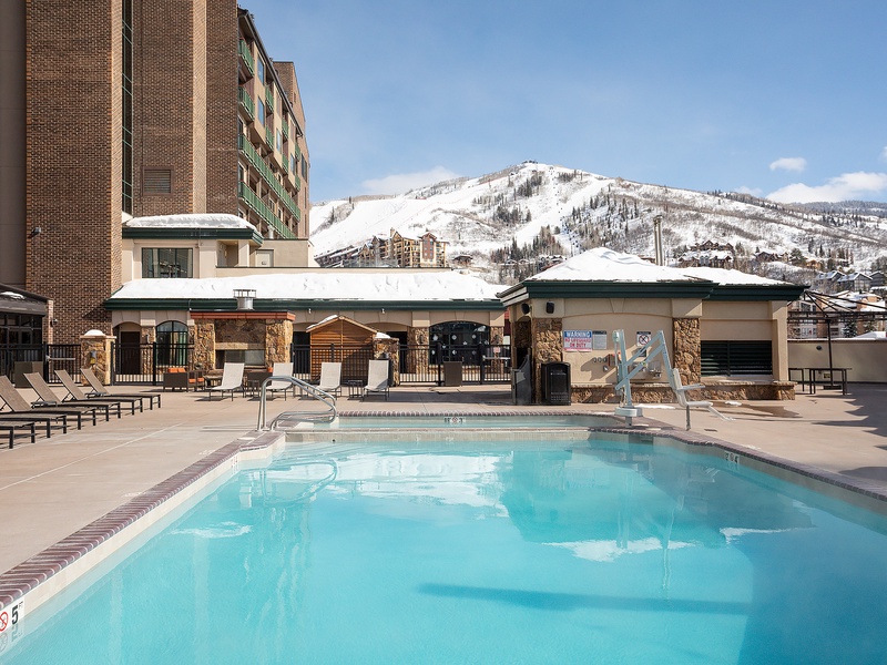 This property features an inviting outdoor pool area framed by dramatic winter mountain views and modern resort-style amenities. Located in a scenic ski town setting with year-round alpine charm.