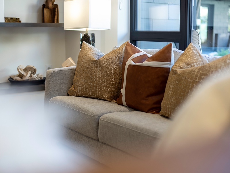 Sink into plush cushions and unwind in your modern living space, where natural light streams through sleek black-framed windows and thoughtful design meets everyday comfort.