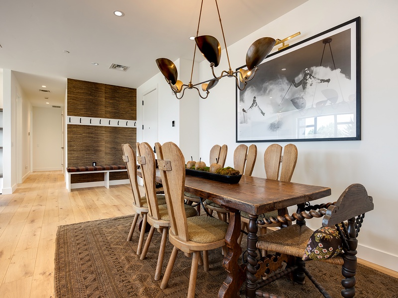 Your dining space awaits with a striking handcrafted table set beneath a sculptural chandelier. Rich wooden floors and artisan details create an inviting atmosphere for memorable meals together.