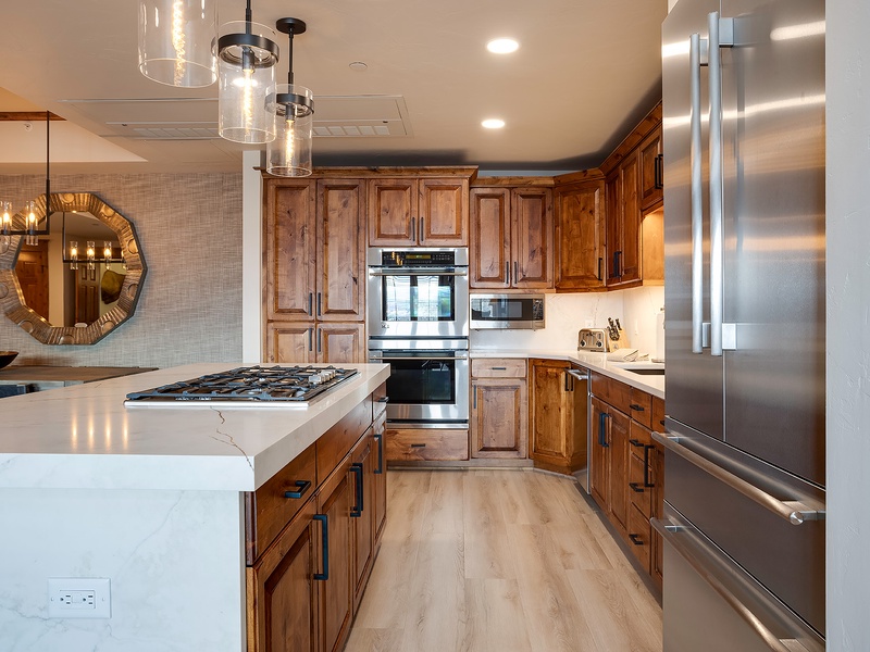 Picture yourself preparing meals in this spacious kitchen, where warm wood cabinetry meets sleek stainless steel appliances and elegant marble countertops invite culinary creativity.