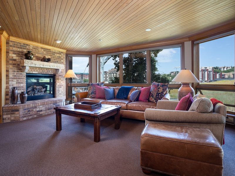 Relax in your bright living room with plush leather seating, a warm fireplace, and sweeping city views through expansive windows—your perfect retreat after a day exploring.