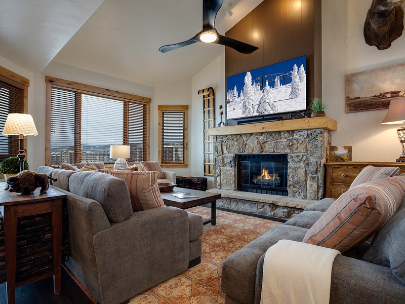 Unwind in your cozy living room with plush seating, a warm fireplace, and mountain views. Vaulted ceilings and rustic décor create a welcoming retreat after a day on the slopes.