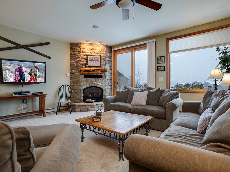 Sink into plush seating beside a glowing stone fireplace as mountain and valley views stretch beyond your windows, blending warmth and natural beauty.