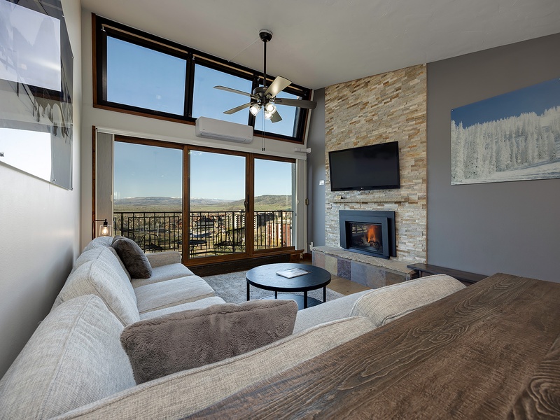 Sink into plush seating and soak up mountain views through floor-to-ceiling windows. The stone fireplace adds warmth while you unwind in your stylish retreat.