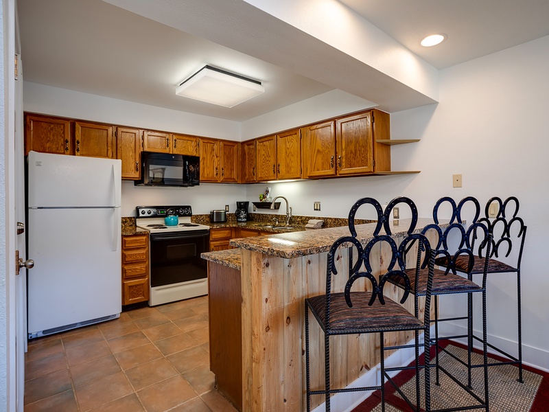 Your fully-equipped kitchen features warm wood cabinetry, granite countertops, and a charming breakfast bar with seating—perfect for preparing meals and gathering with family.