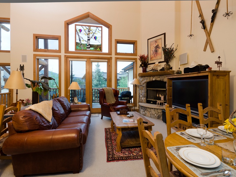 Sink into plush leather sofas as natural light floods through soaring windows, framing mountain views. Warm your evenings by the stone fireplace, gather around the rustic dining table, and let the cozy lodge atmosphere make you feel right at home.