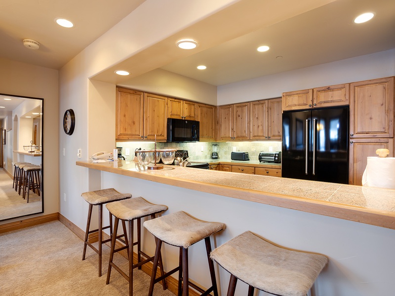 Gather around this spacious kitchen with warm wood cabinetry and a generous breakfast bar where your mornings unfold with coffee and conversation.