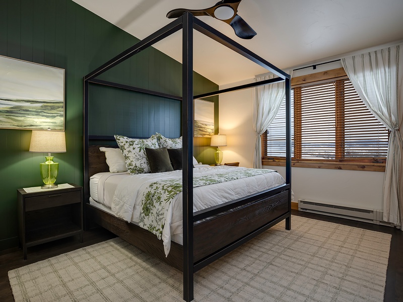 Drift off in this elegant canopy bed with botanical linens, surrounded by calming green walls and soft lamplight that create your perfect retreat.