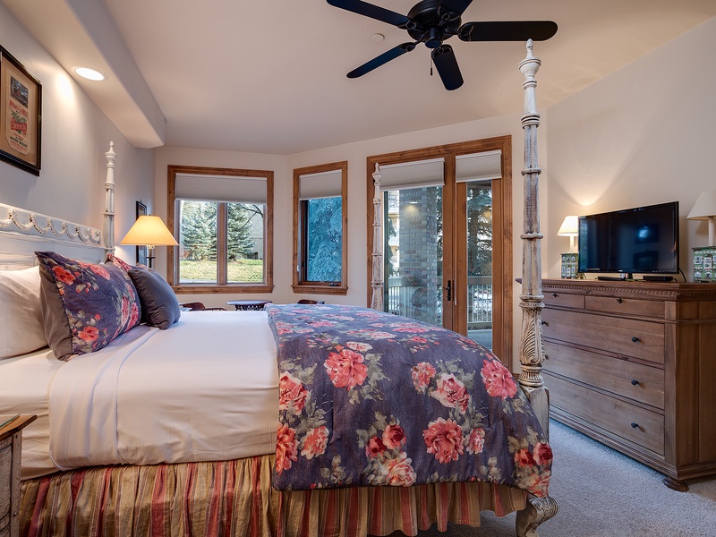 Wake up in this inviting bedroom with views of evergreen trees and snowy slopes just beyond your window. The elegant four-poster bed, warm wood furnishings, and cozy ceiling fan create your perfect mountain retreat.