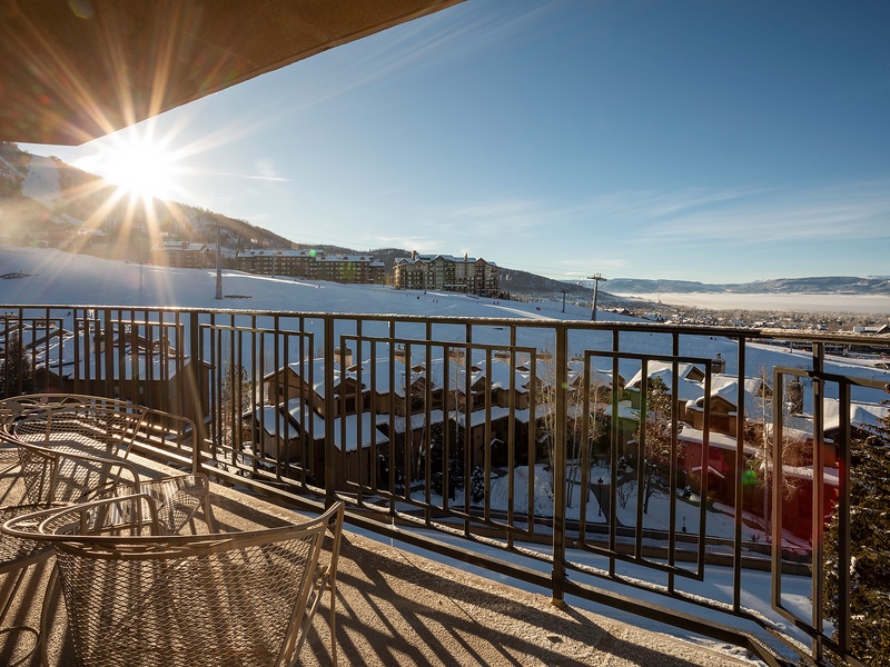 A bright winter morning greets the property, with snow-covered slopes rising above the valley below and sunshine streaming across nearby buildings and rooftops.