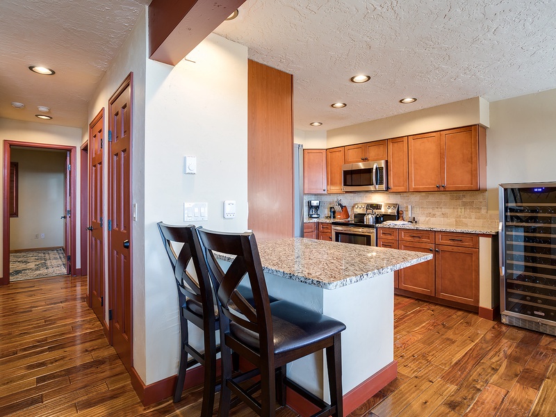 Your fully-equipped kitchen features warm wood cabinetry, granite countertops, stainless appliances, and a breakfast bar perfect for morning coffee or casual meals together.