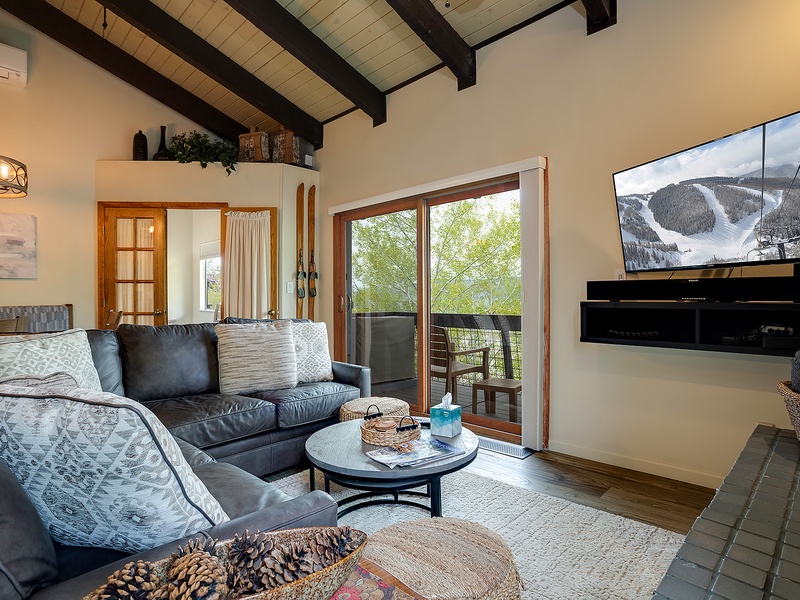 Relax in your spacious living room with exposed beam ceilings, where you can unwind on plush sofas, enjoy mountain views through the balcony doors, and catch your favorite shows on the large flat-screen TV.