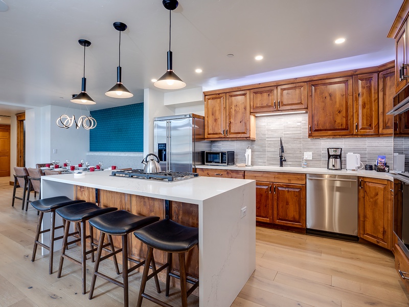 Gather around the spacious island in your gourmet kitchen, featuring warm wood cabinetry, sleek stainless appliances, and a gas cooktop—perfect for preparing meals together and creating lasting memories.