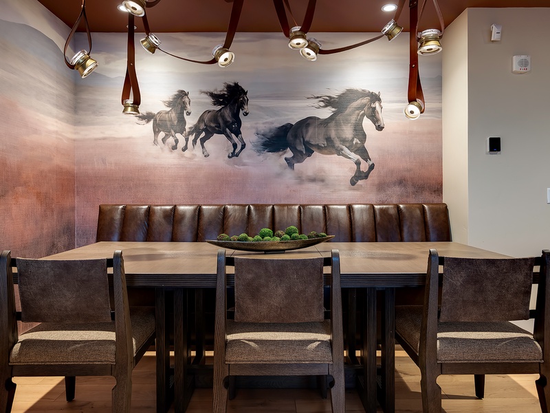 Your private dining space invites unforgettable meals beneath dramatic lighting and stunning artwork. Settle into the tufted leather banquette and savor every moment around this handsome table designed for togetherness.