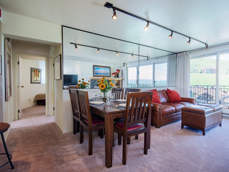 Relax in your open-concept living and dining space, where large windows frame stunning views. The leather sofa invites you to unwind, while the dining table awaits memorable meals together.
