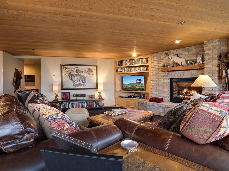 Sink into plush leather couches by your crackling fireplace, perfect for cozy evenings with loved ones. Western charm meets comfort in this inviting living space designed for relaxation.