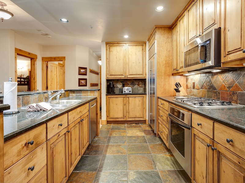 Your fully equipped kitchen with warm wood cabinetry, granite countertops, and stainless appliances invites you to cook meals just like home in a beautifully designed space.