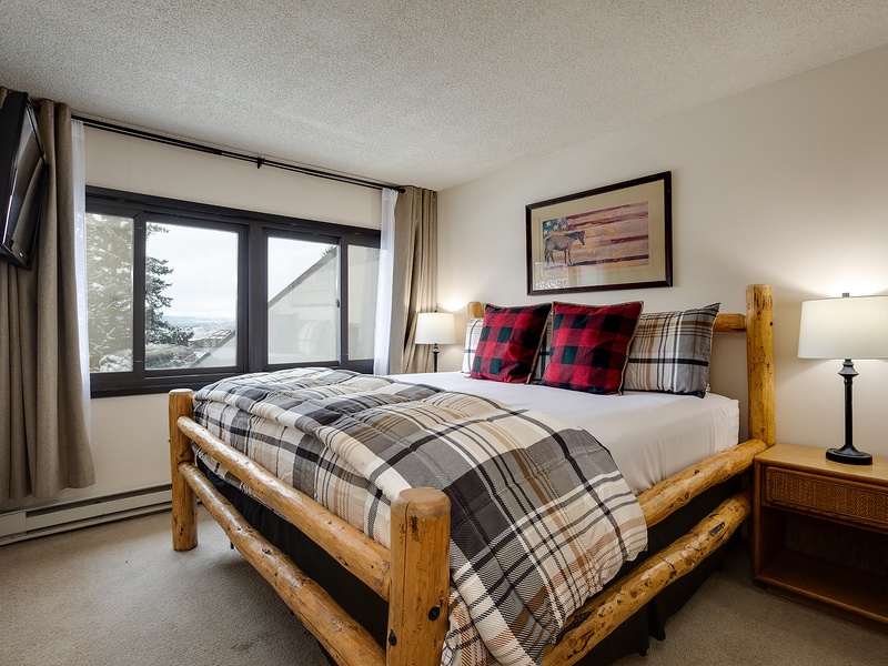 Wake up to stunning views through your bedroom window. Cozy plaid bedding and rustic log furniture create a welcoming mountain retreat where you'll rest deeply after your adventures.