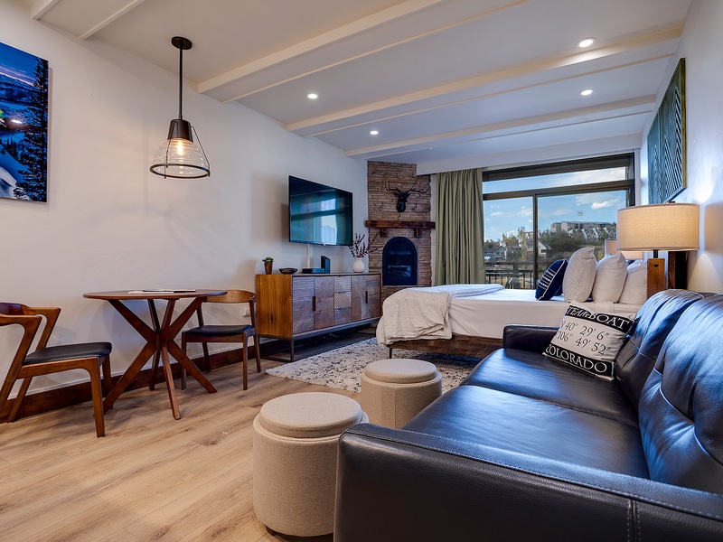 Unwind in your open-concept retreat with cozy fireplace, plush bedding, and a welcoming lounge area. Enjoy mountain views through expansive windows, a fully equipped dining nook, and modern comfort throughout your stay.