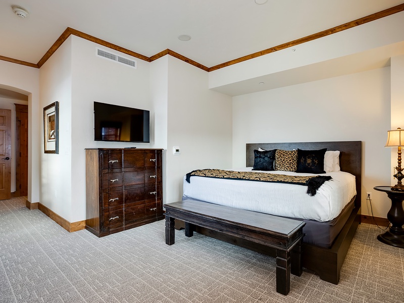 Sink into your plush bed after a day of adventure. Dark wood accents and warm lighting create a restful sanctuary where you'll unwind in comfort and style.
