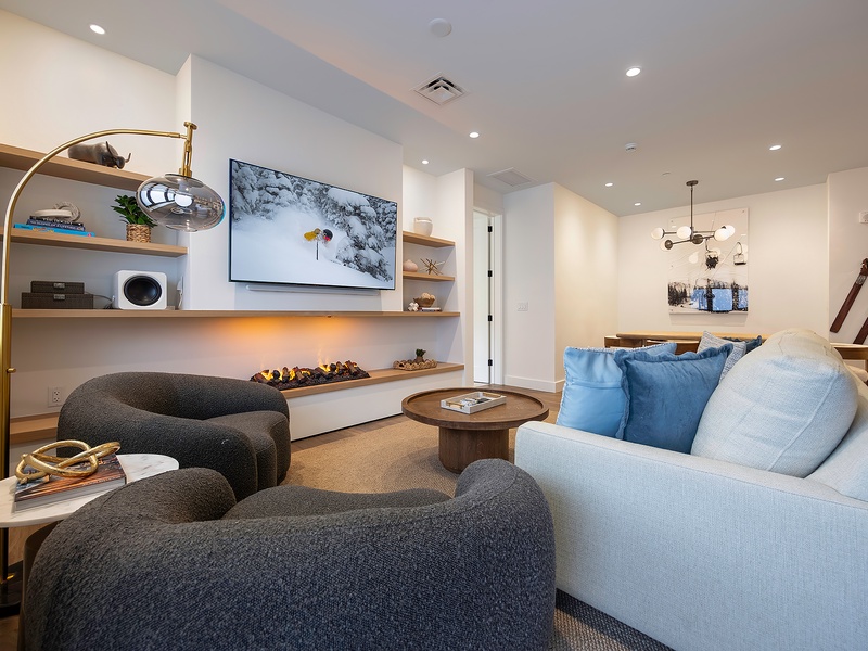 Settle into your stylish living space, where modern design meets coastal calm. Curved seating and warm lighting invite you to unwind after a day exploring, while natural textures create a soothing retreat.